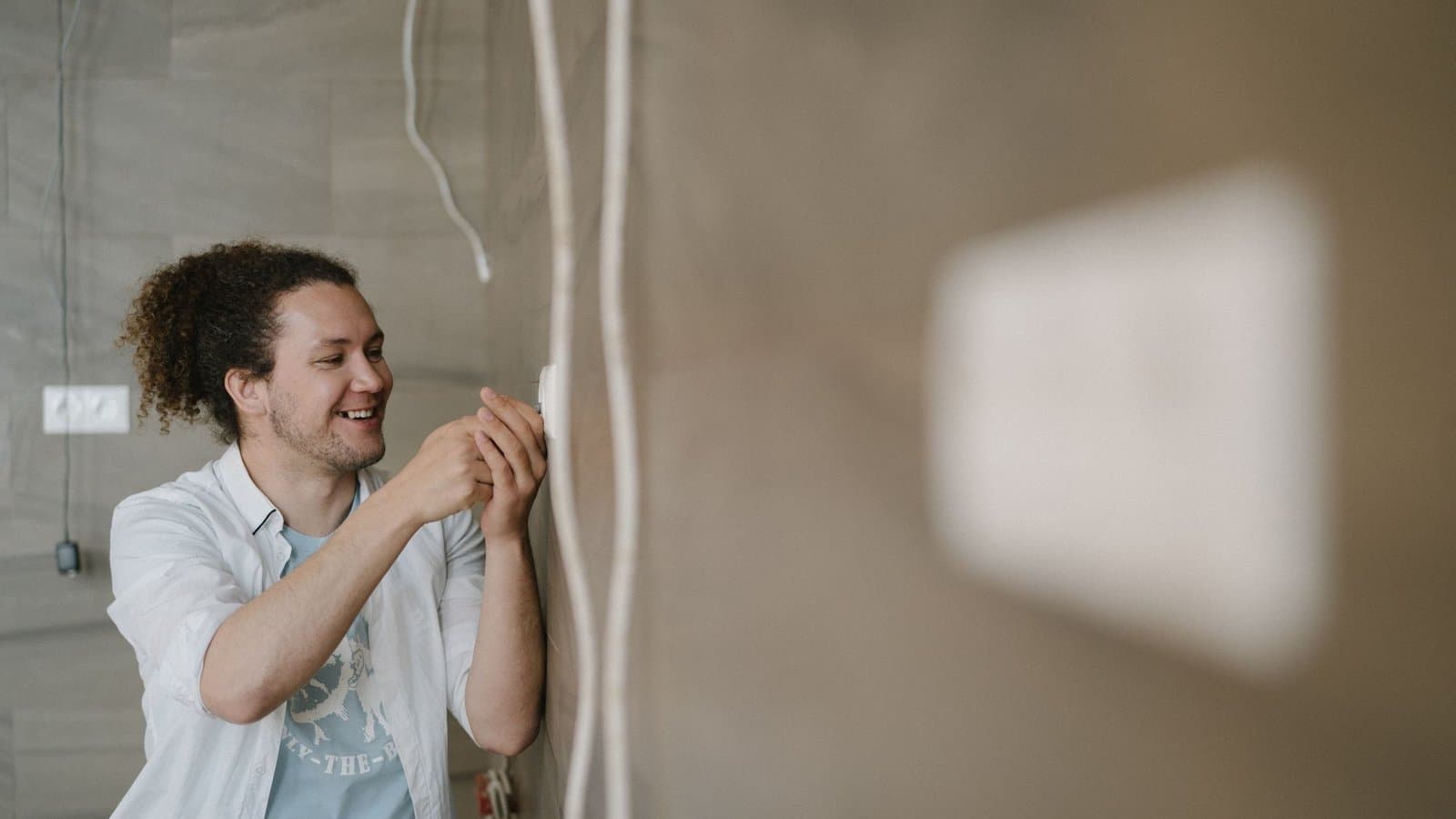 Un électricien installe un câble dans un appartement