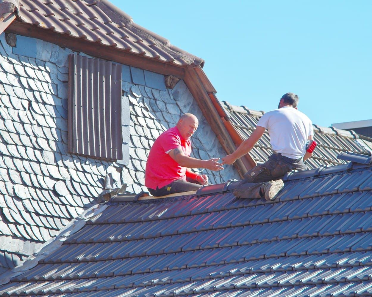 Deux couvreurs travaillent sur un toit en ardoise