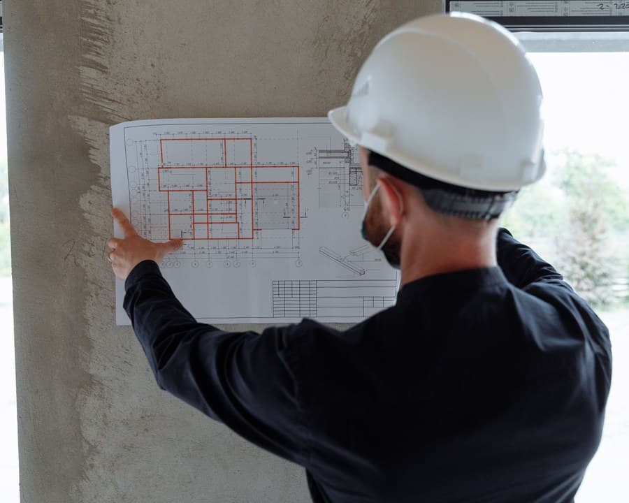 Un dessinateur casqué vérifie son plan sur le chantier