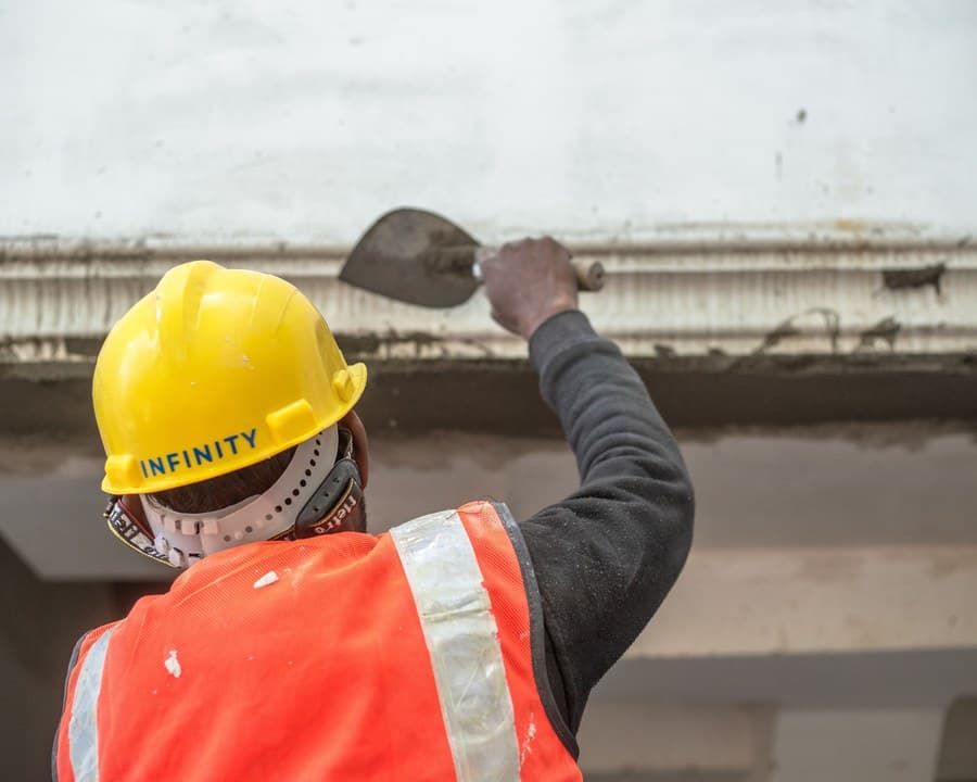 Un façadier casqué lisse un enduit de façade