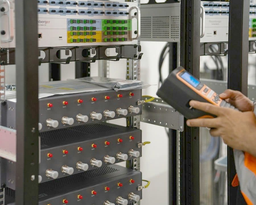 Un technicien mesure une baie optique avec un appareil de test
