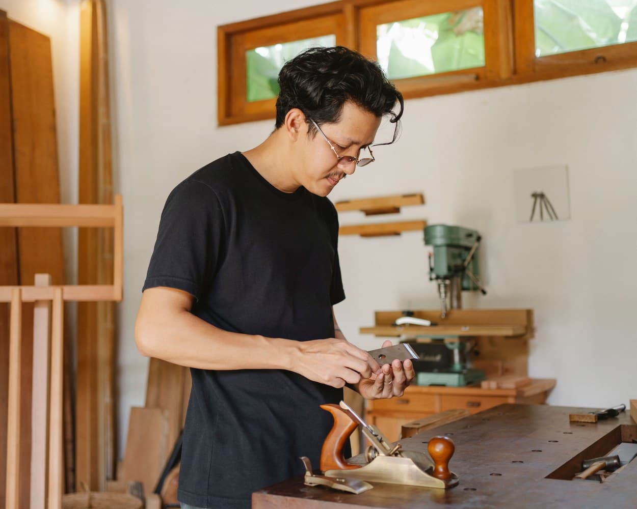 Un menuisier rabote une pièce de bois dans son atelier