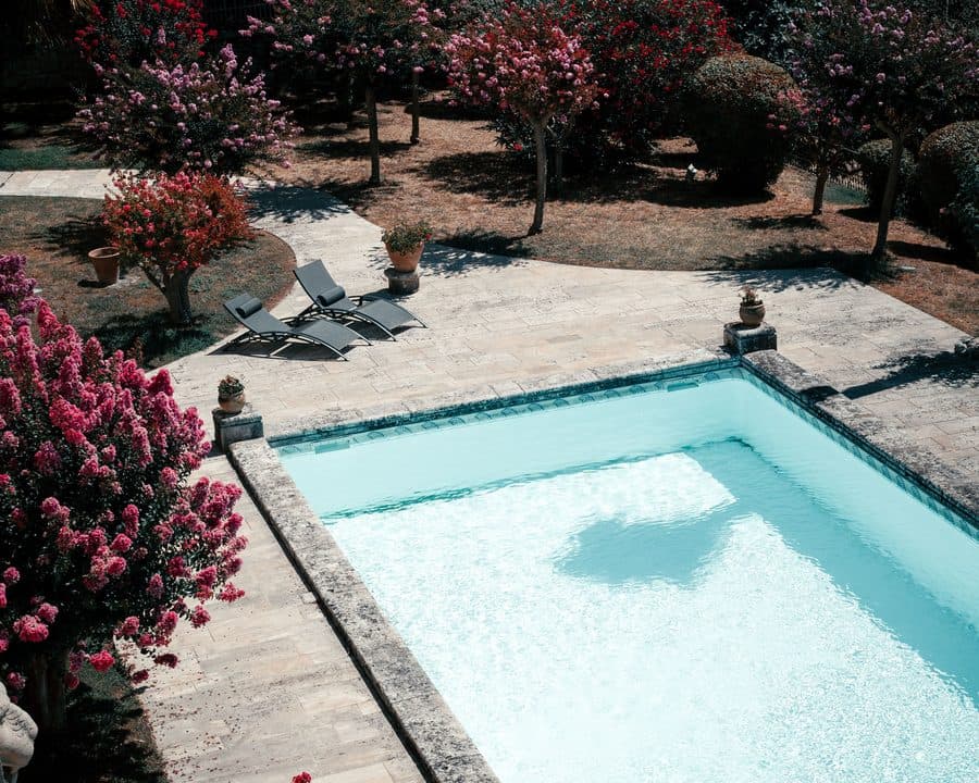 Un bassin en eau, margelles en pierre, jardin fleuri autour