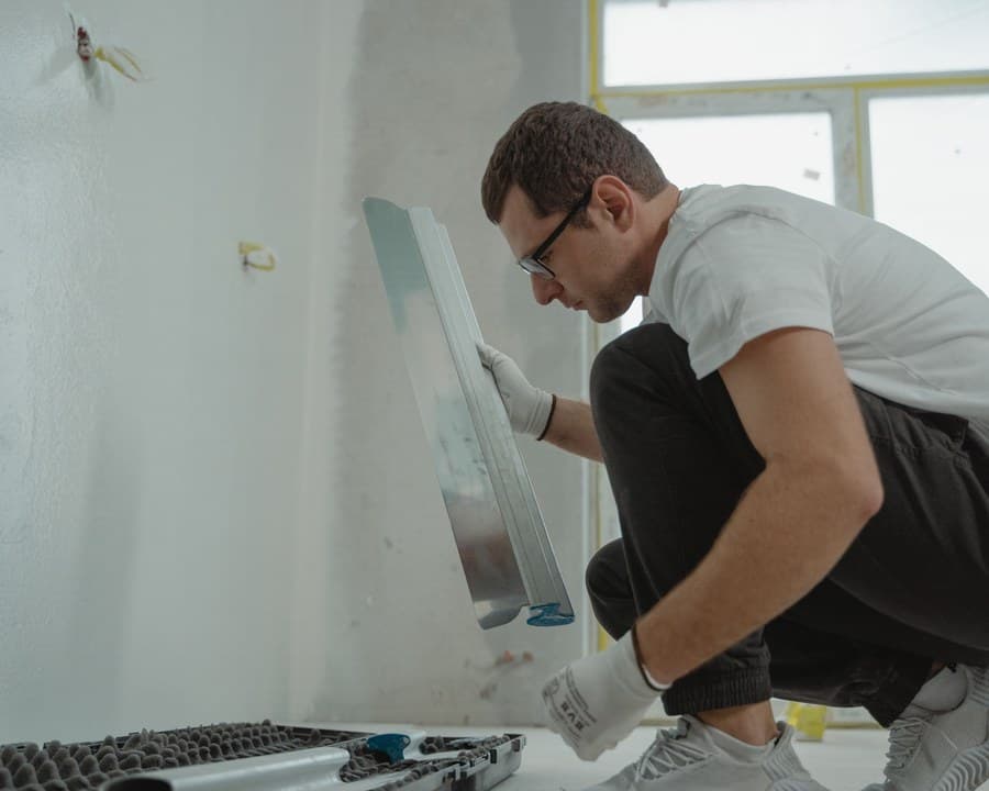 Un plaquiste lisse un mur à la spatule