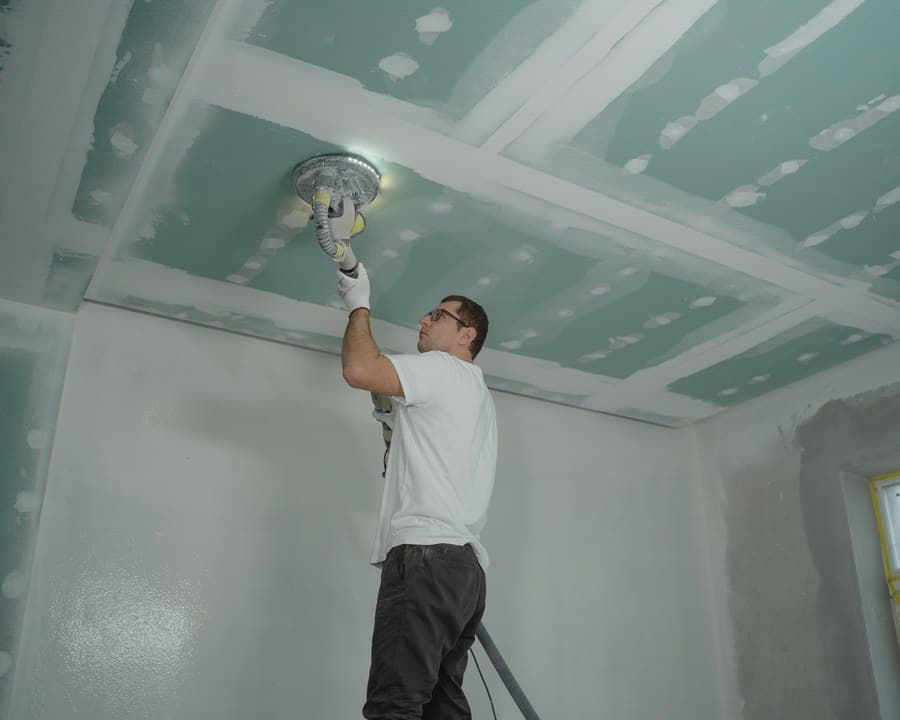 Un plaquiste ponce les joints d’un plafond
