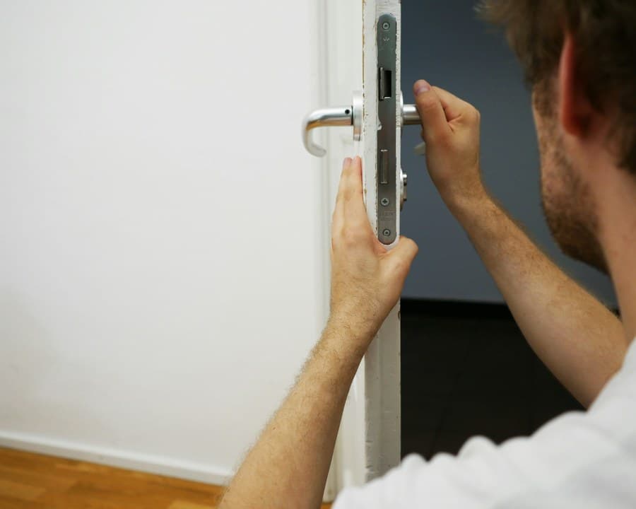 Un serrurier ajuste une serrure de porte