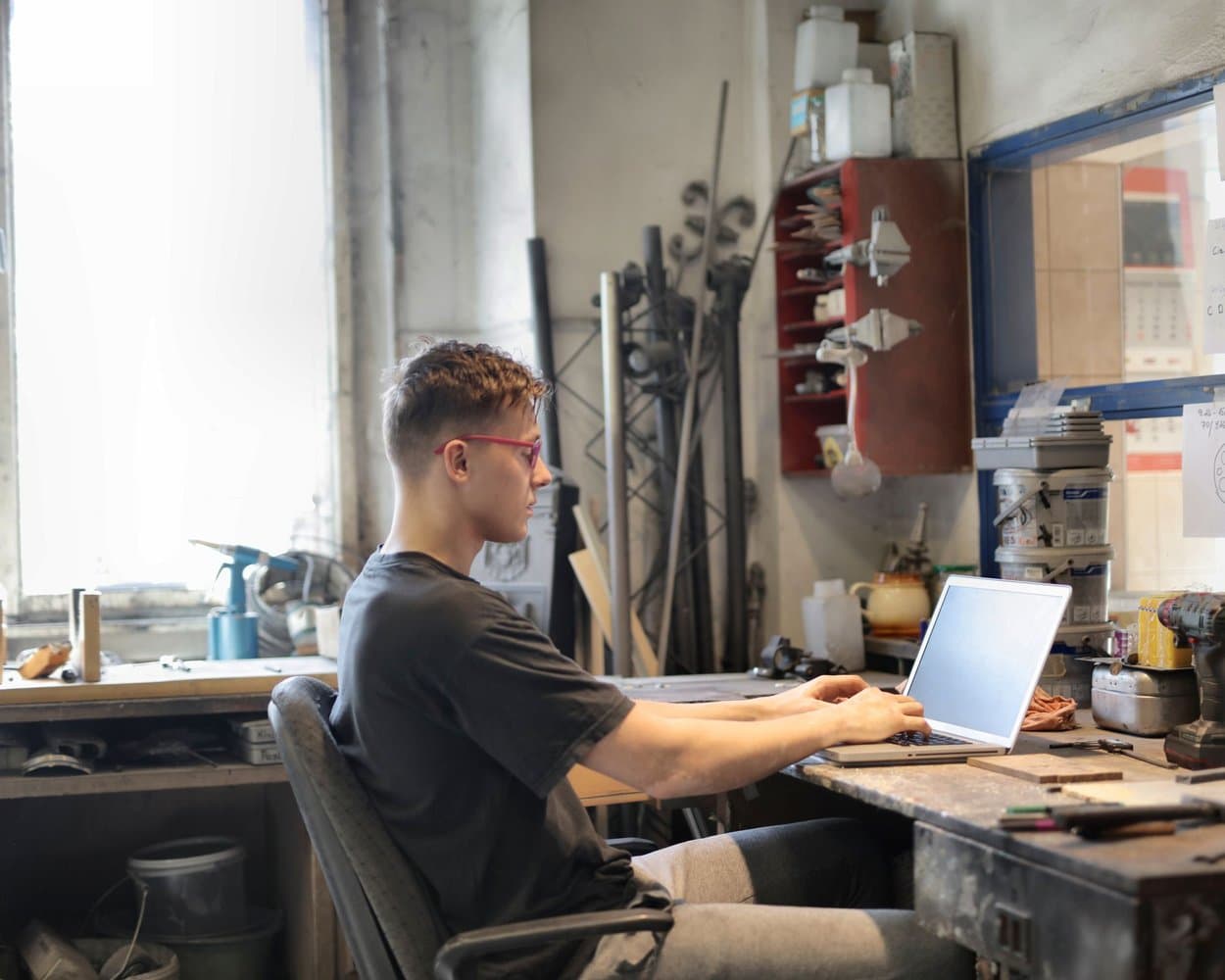 Un artisan travaille sur son ordinateur portable, au bureau de son atelier