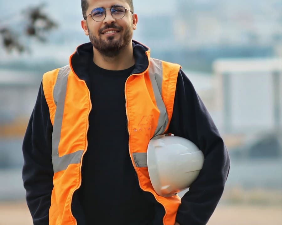Un ouvrier en gilet orange, casque sous le bras