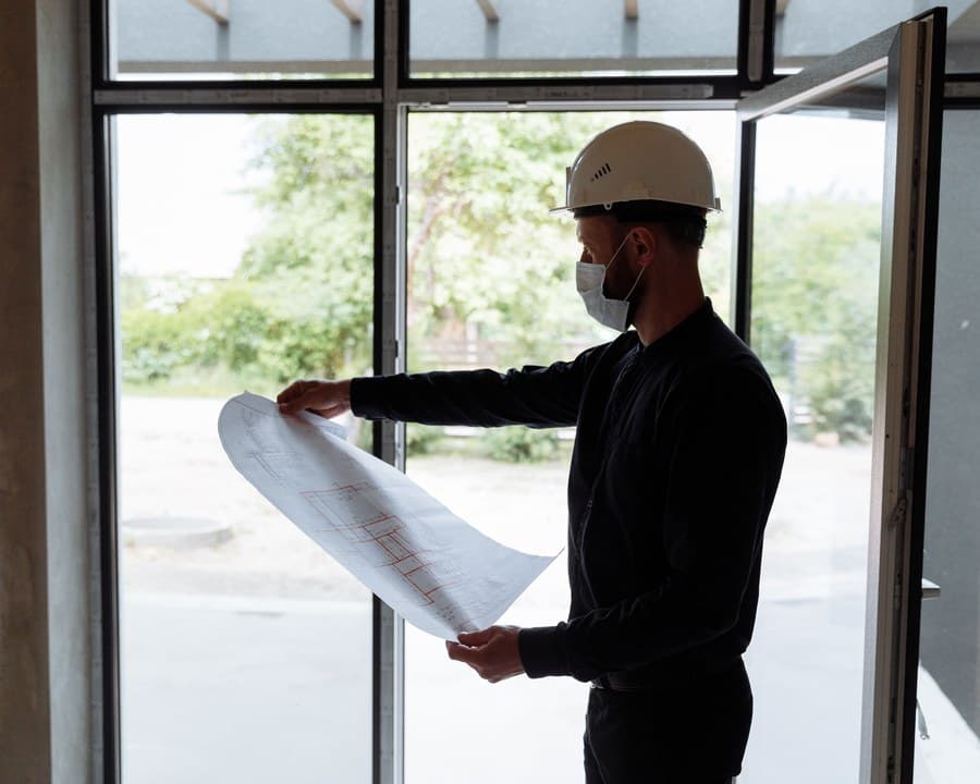 Un maître d’œuvre vérifie un plan dans un bâtiment en chantier