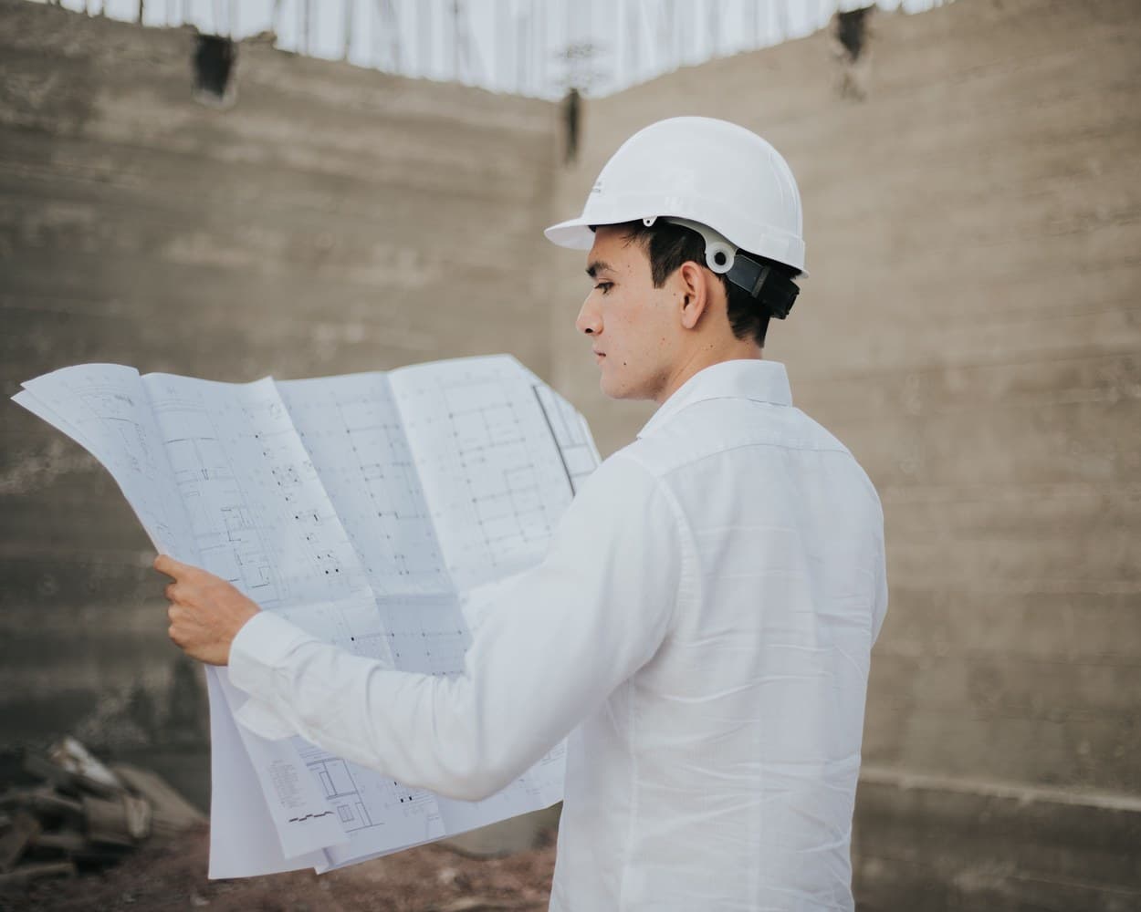 Un maître d’œuvre casqué lit un plan sur le chantier