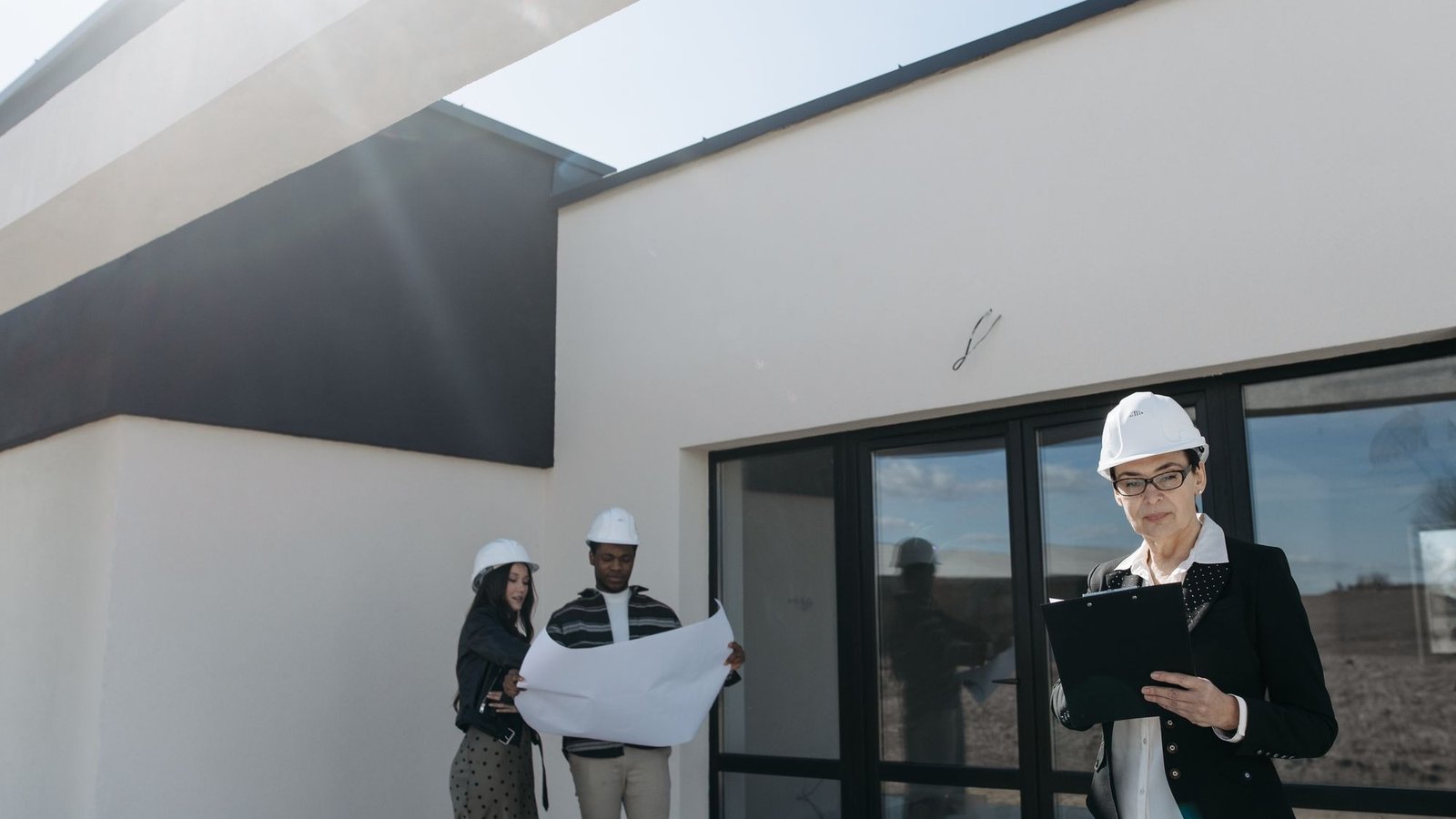 Une professionnelle du bâtiment lit un document devant une maison neuve