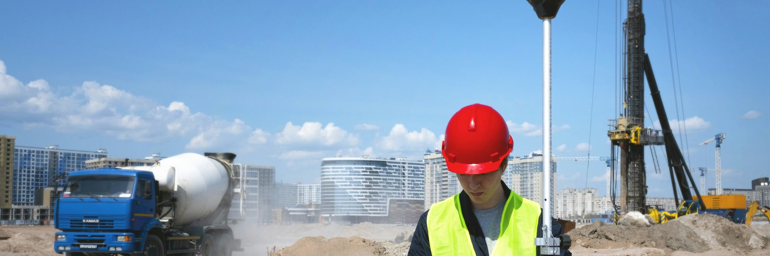 Un ouvrier casqué lit son téléphone sur un chantier