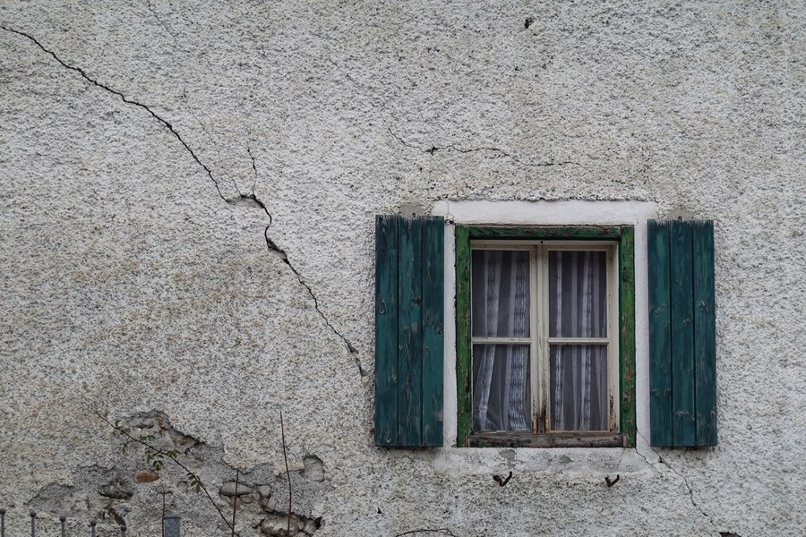 Une fissure court sur le mur d’une façade, autour d’une fenêtre